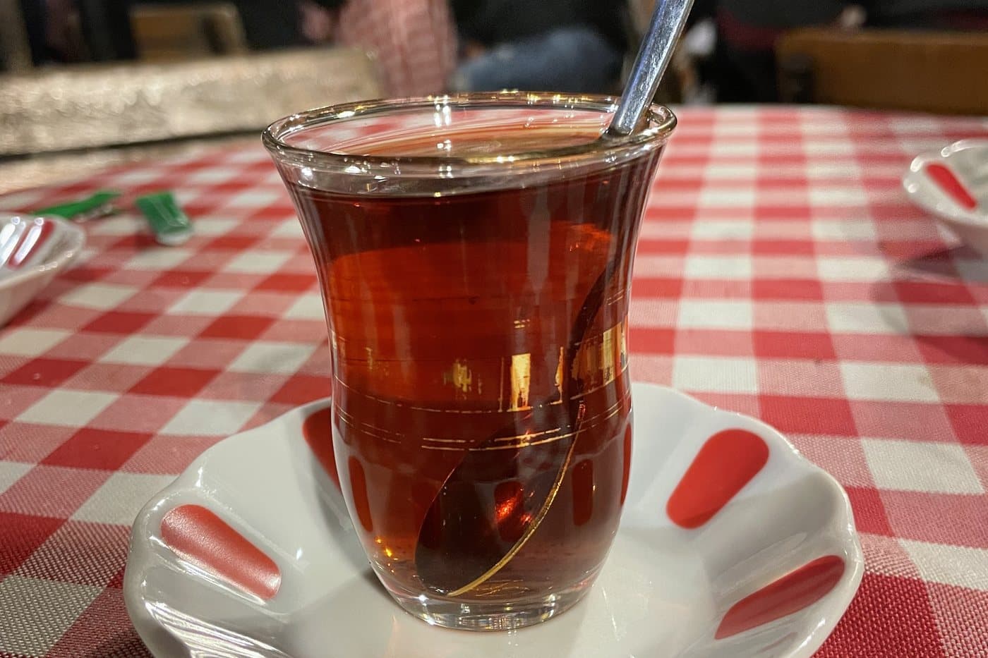 Kareli masa örtüsünde ince belli bardakta demli çay, kaşığı bardağın içinde