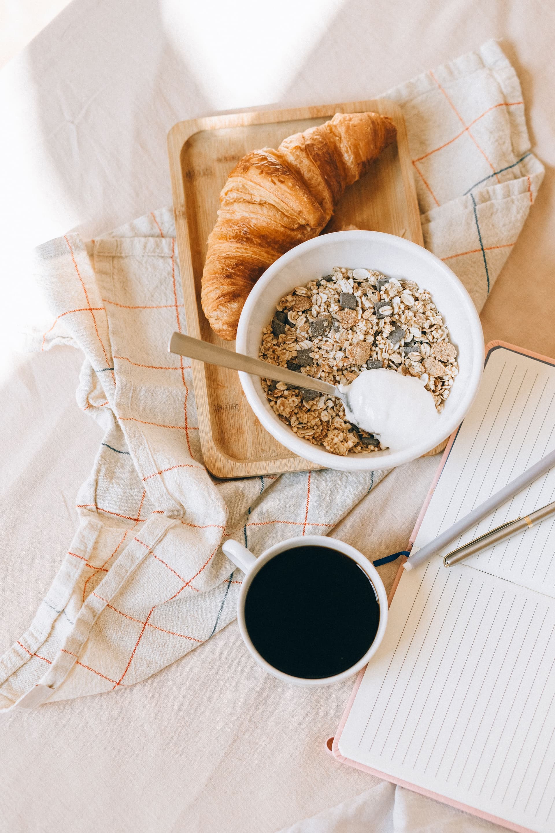 Kahve, granola kâsesi ve kruvasandan oluşan kahvaltı sofrası