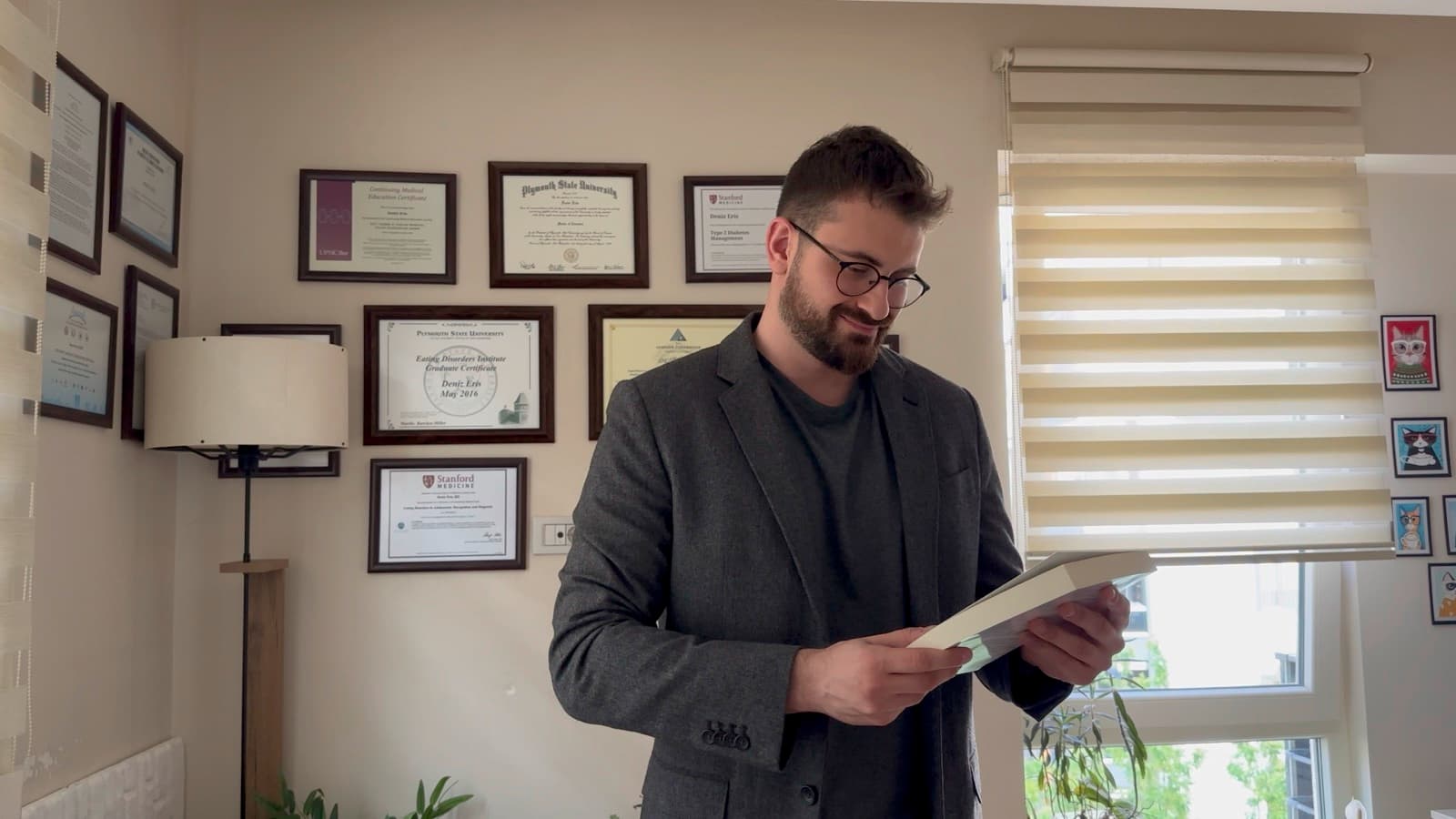 Uzm. Dyt. Deniz Eriş, kliniğinde diploma ve sertifikalarının önünde danışan dosyasını incelerken