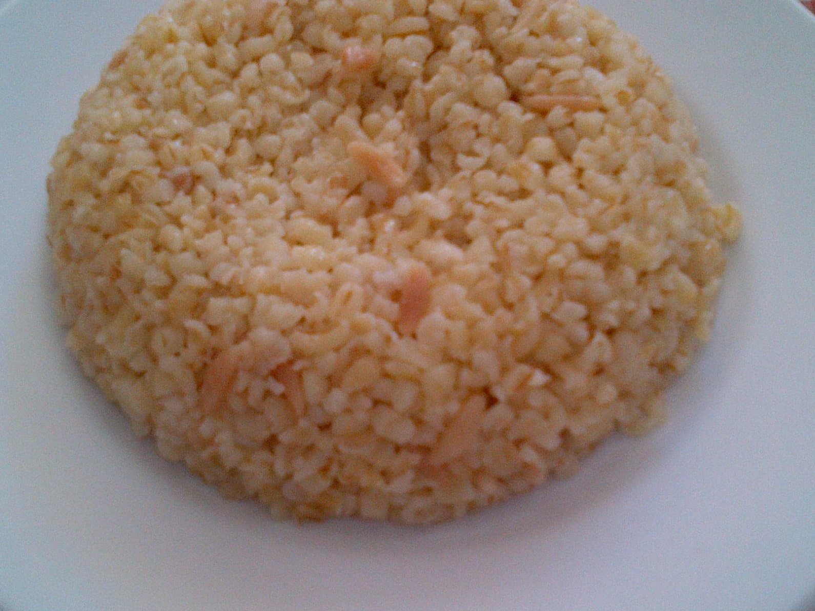 Beyaz tabakta kalıplanmış bulgur pilavı, tane tane bulgur ve aralarında ince şehriye görünüyor