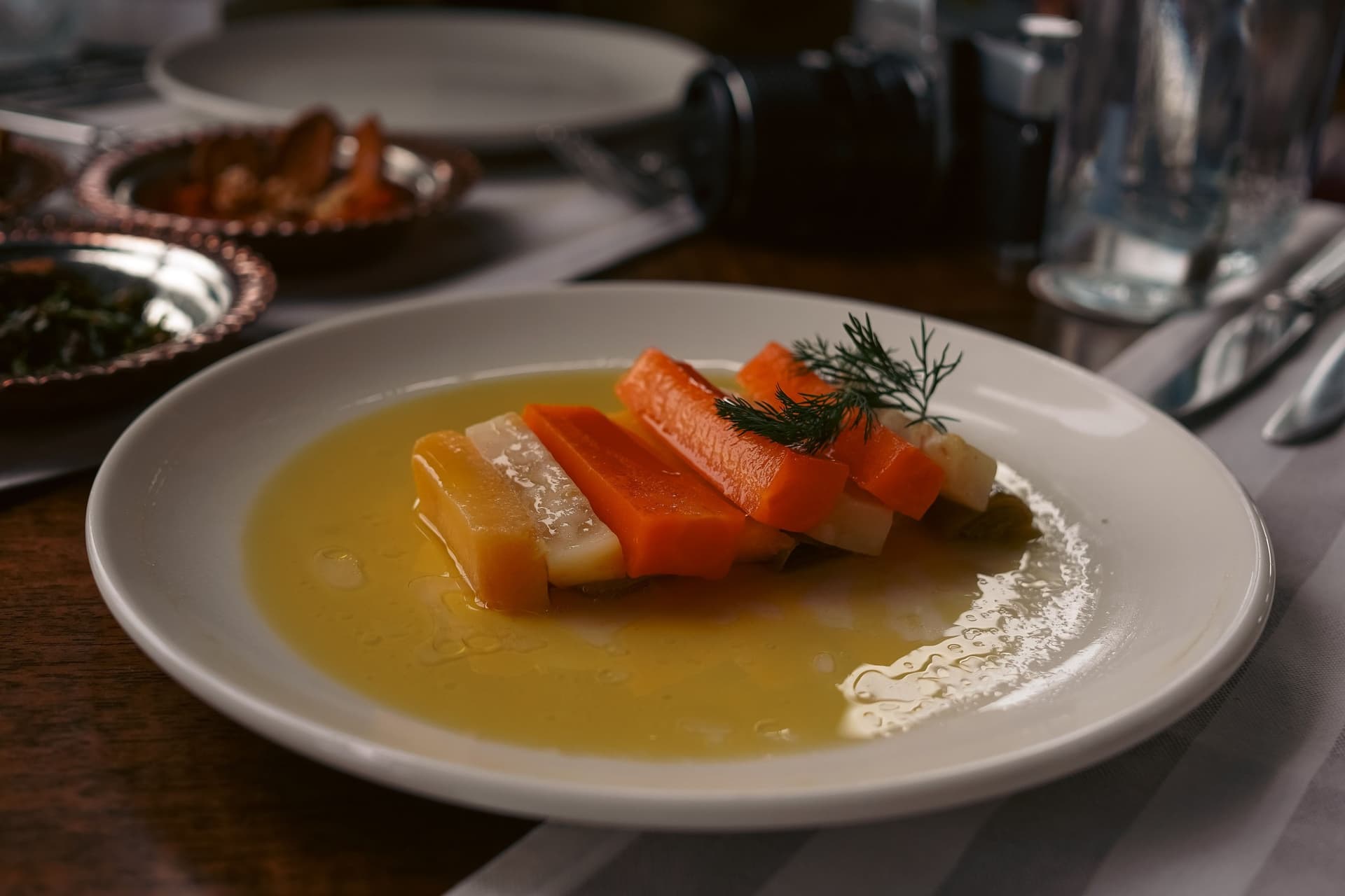 Beyaz tabakta limonlu zeytinyağı sosunda kereviz ve havuç dilimleri, üzerinde bir dal dereotu