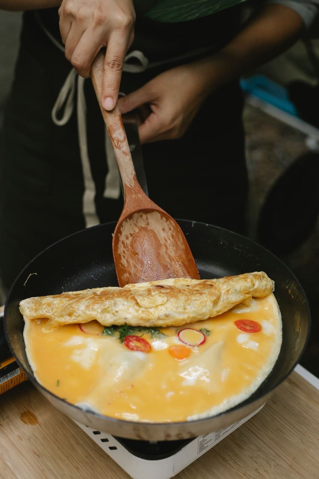 Tavada katlanan sebzeli omlet: yumurtanın içinde kırmızı biber halkaları ve yeşil otlar