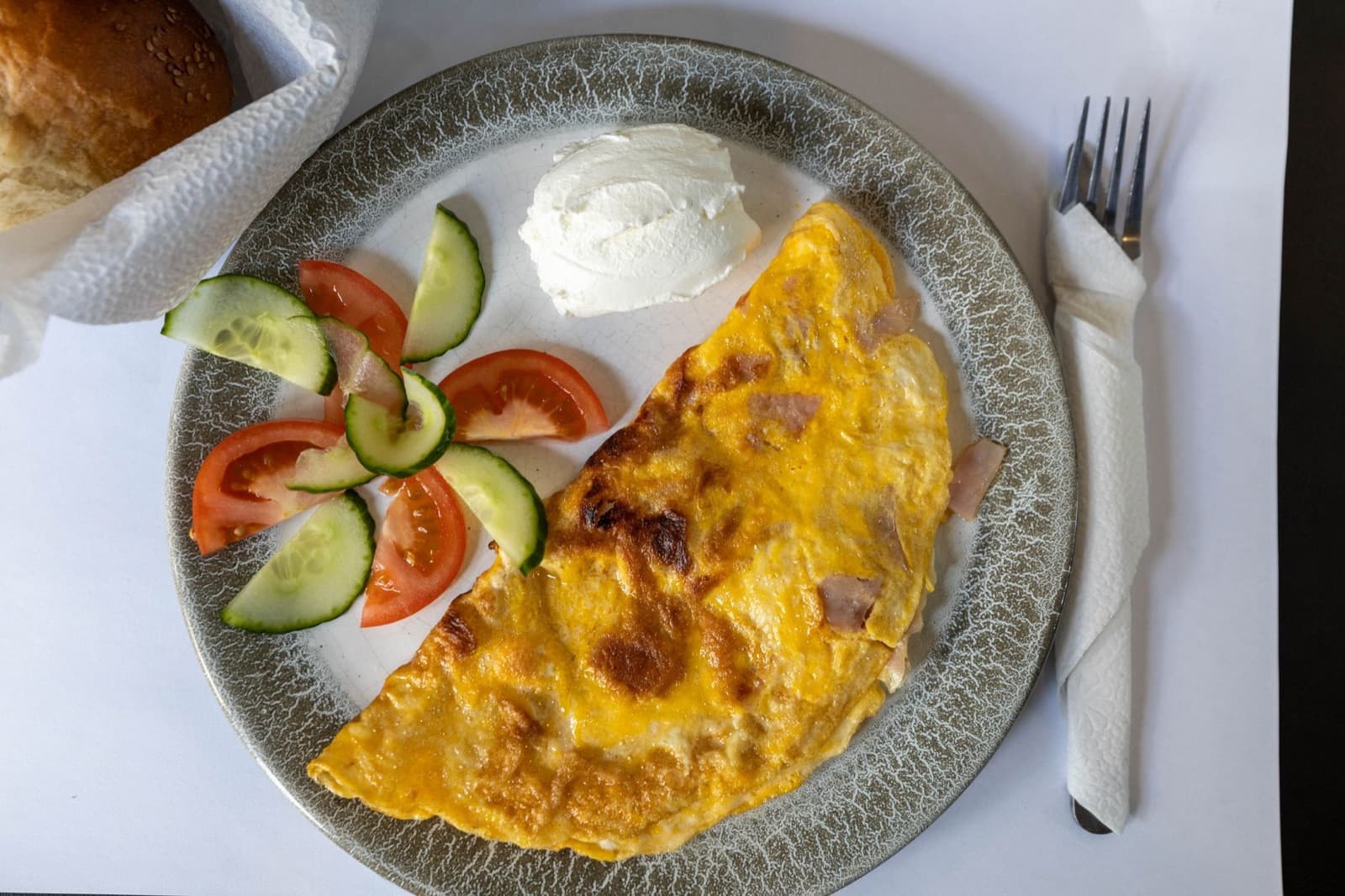 Tabakta katlanmış omlet, yanında avokado, domates ve yoğurt