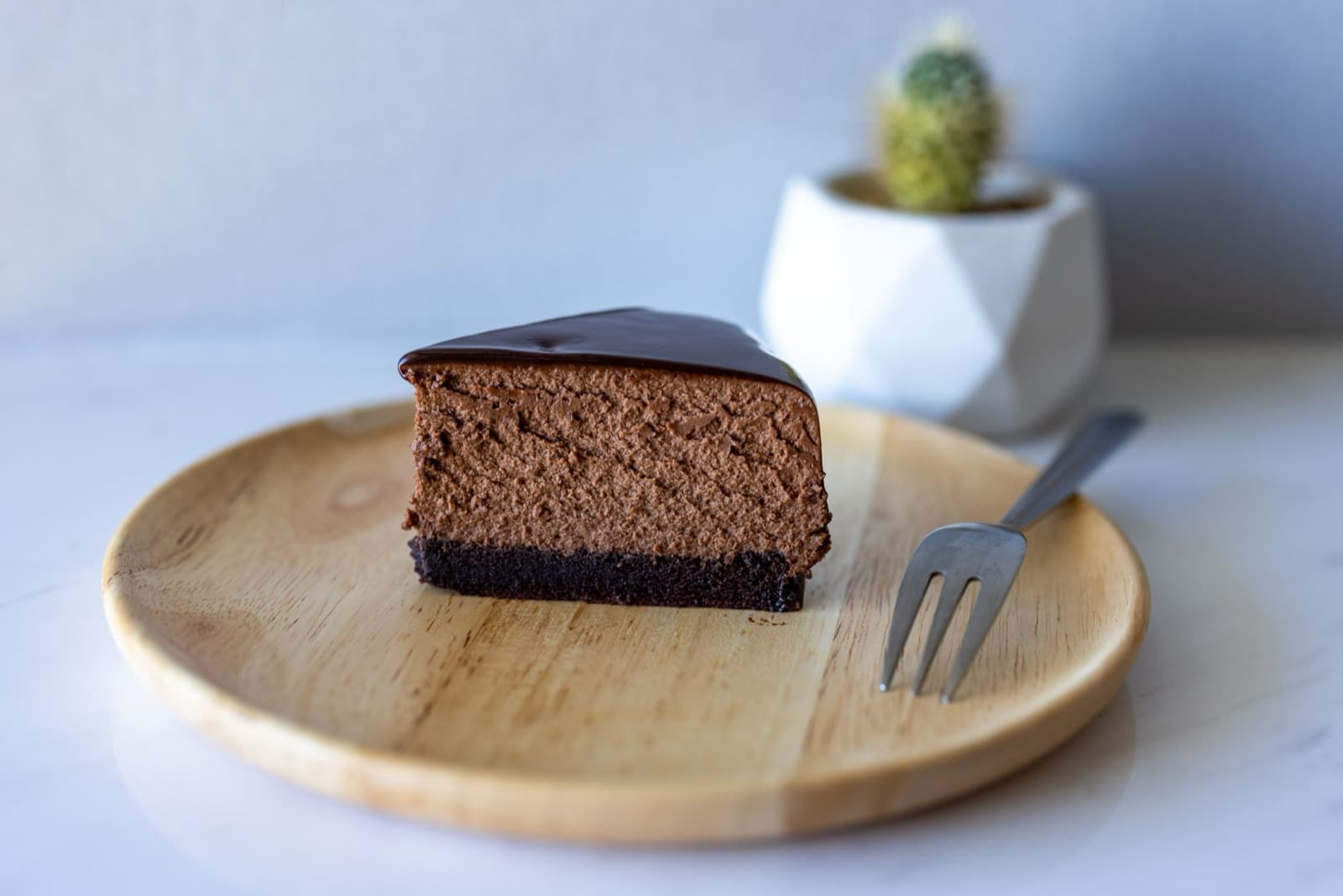 Ahşap tahtada koyu çikolatalı cheesecake dilimi ve çatal