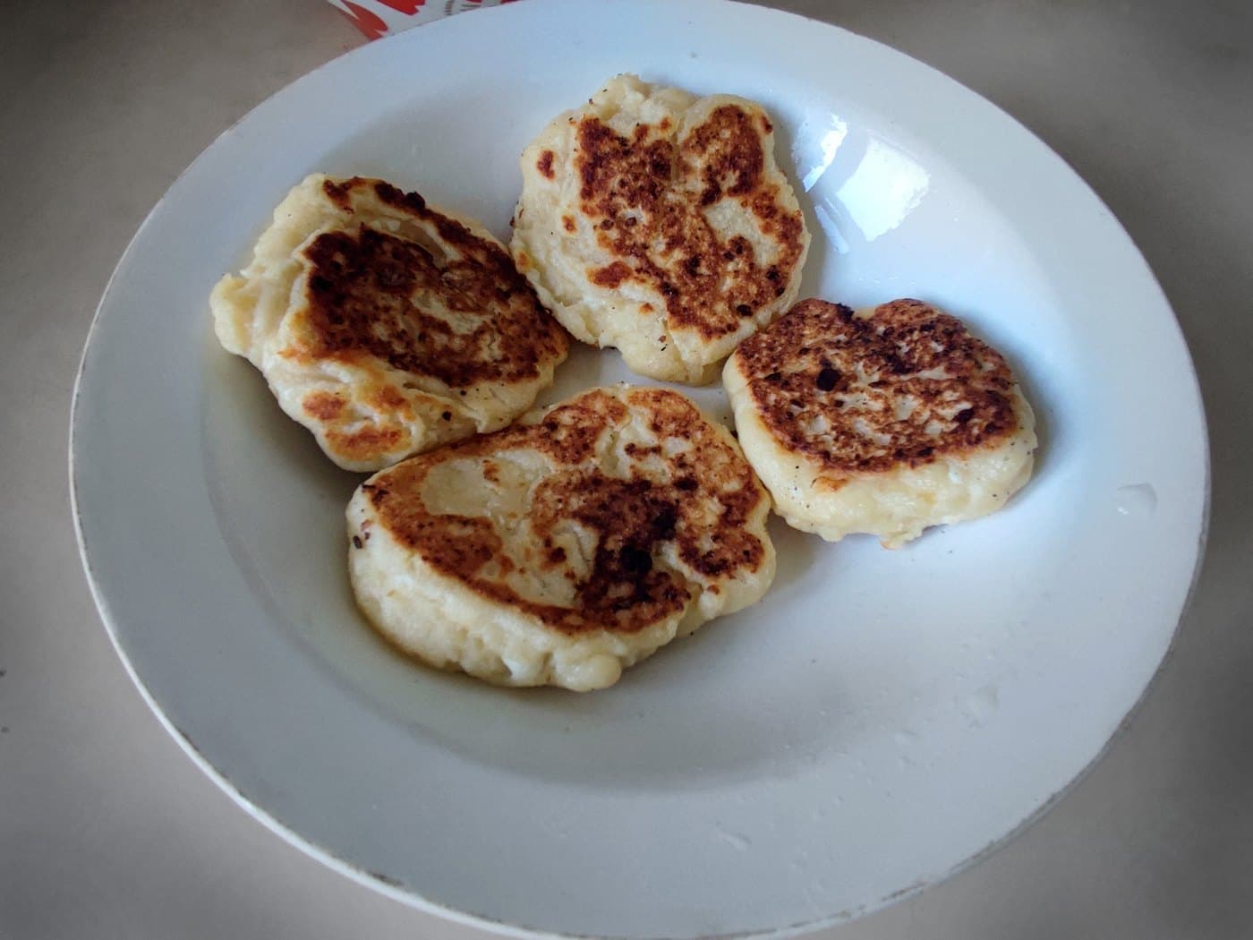 Açık mavi tabakta tavada pişmiş, yüzeyleri altın rengi lor köfteleri